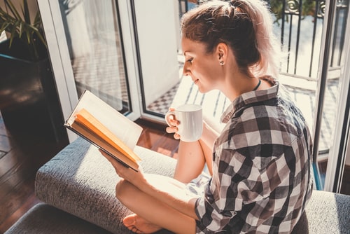 女性がコーヒーを飲みながら本を読んでいる画像