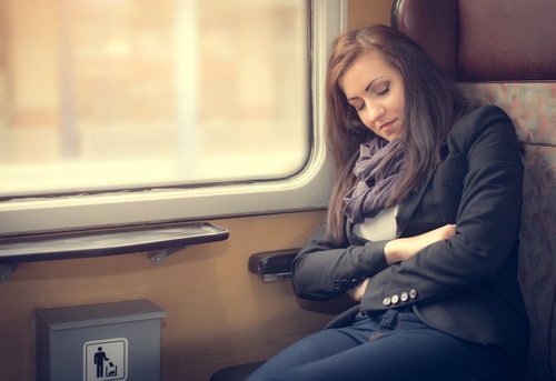 女性が電車の中で座って眠っている画像