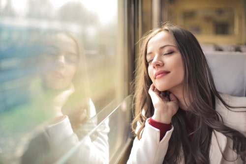 女性が電車に座って黄昏ている画像
