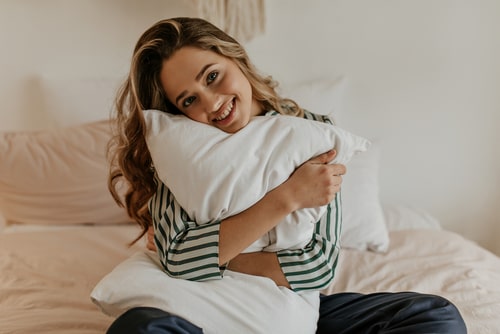 女性が枕を抱き抱えている画像