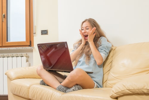 女性がパソコンを見て嬉しそうにしている画像